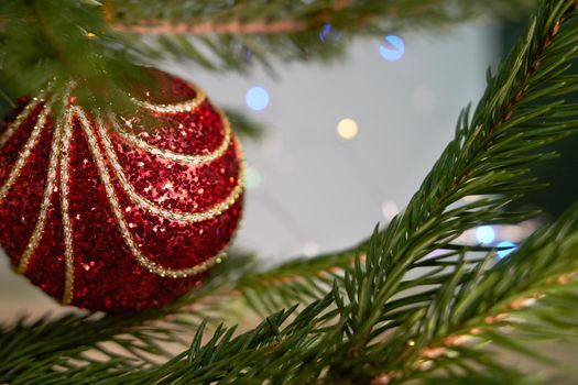 Cropped image of christmas tree with red toy in room. Soft selective focus