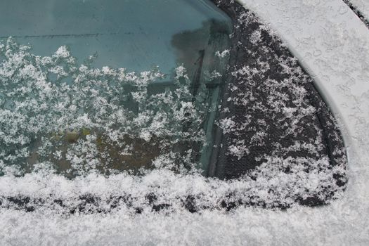 Snow-covered car window, natural background, first snow. Close-up