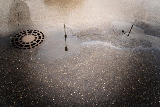 Oil slick on the asphalt road background drains into the storm drain.Water pollution environmental problems