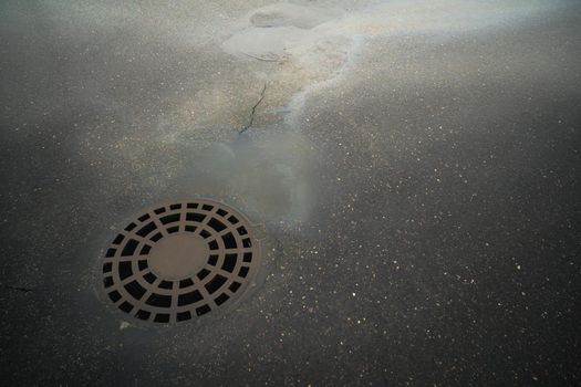 Oil slick on the asphalt road background drains into the storm drain.Water pollution environmental problems