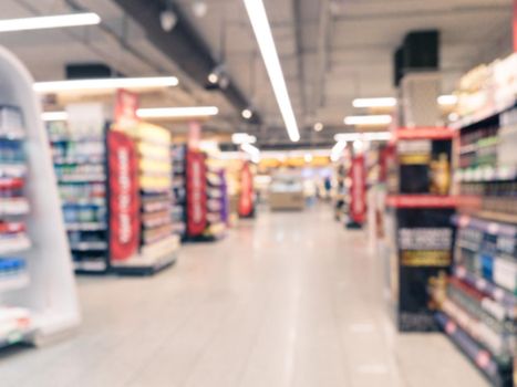 Abstract blurred supermarket aisle with colorful shelves and unrecognizable customers as background