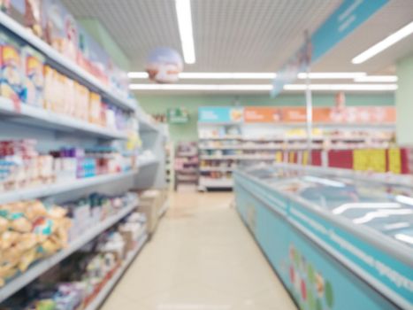 Abstract blurred supermarket aisle with colorful shelves and unrecognizable customers as background