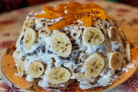 Homemade cake decorated with bananas and peach chunks, sprinkled with showolad. Close up