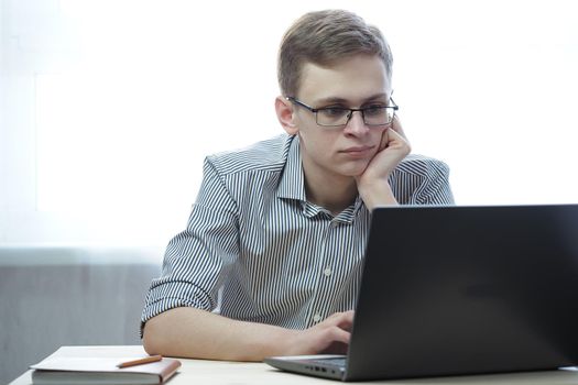 Remote work or online education. A young man with glasses behind a laptop screen. High quality photo