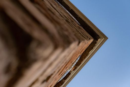 Corner of an old building seen up close and from below with a blue sky.