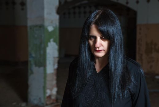 portrait of young goth woman in an abandoned building. indoor closeup