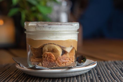 Tiramisu with banana in transparent glass.