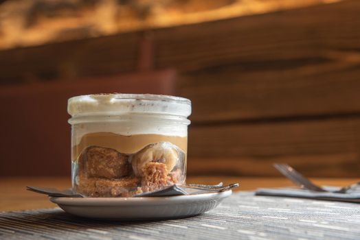 Tiramisu with banana in transparent glass.