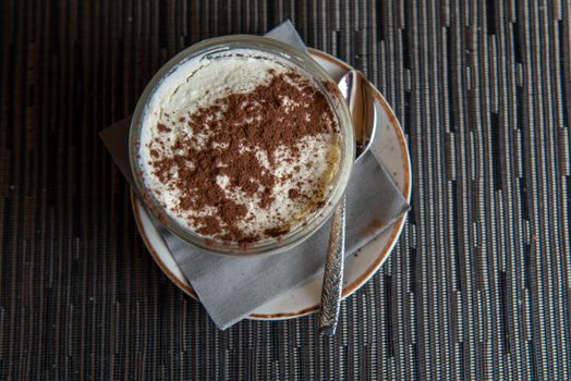 Tiramisu with banana in transparent glass.