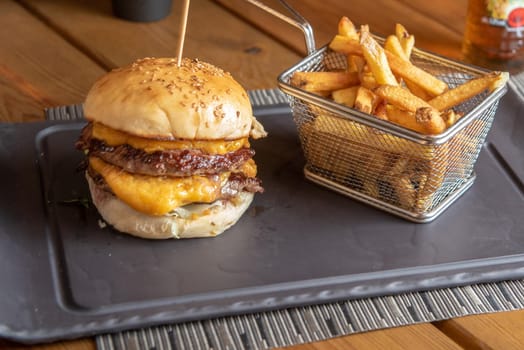 Homemade hamburger with french fries on black stone flat.
