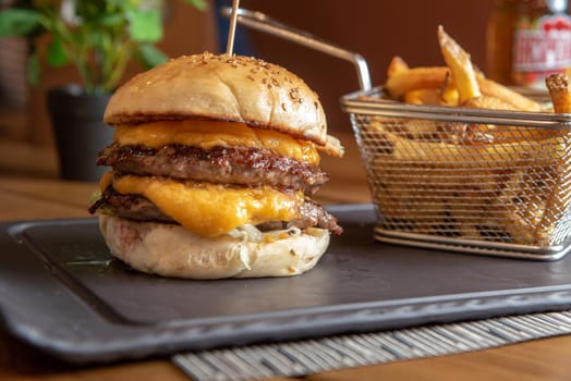 Homemade hamburger with french fries on black stone flat.