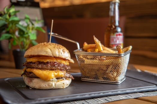 Homemade hamburger with french fries on black stone flat.