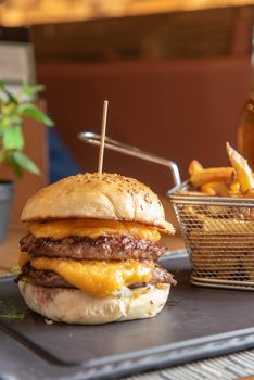 Homemade hamburger with french fries on black stone flat.