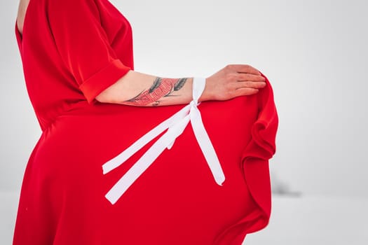 Beautiful woman in a red dress posing outside on a snowy field. She is wearing red dress and have tattoo on her arm.