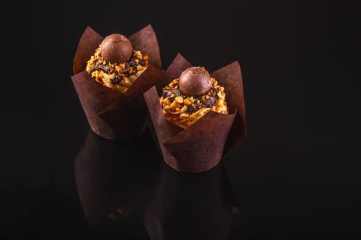 Two Peanut Butter Cupcakes On A Black Background With Reflection.