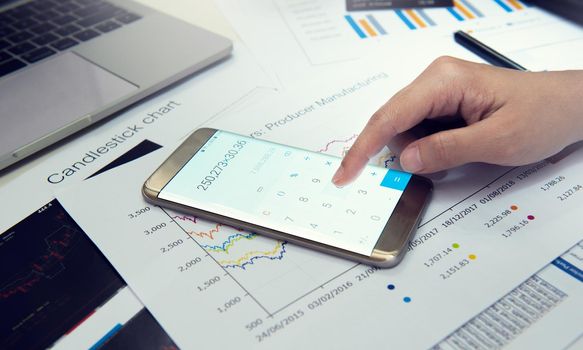 Close-up businessman 's hands using calculation in smart phone at office desk.