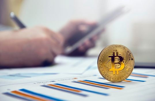 Close-up golden bitcoin on the office desk with businessman working background.