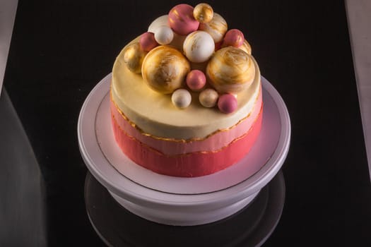 Chocolate layered cake with ganache cream and pink confiture. Decorated with purple and gold chocolate spheres.