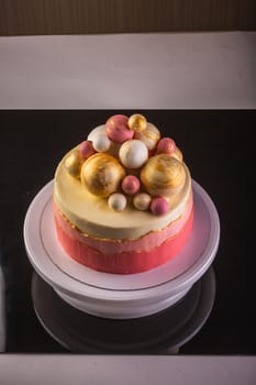 Chocolate layered cake with ganache cream and pink confiture. Decorated with purple and gold chocolate spheres.