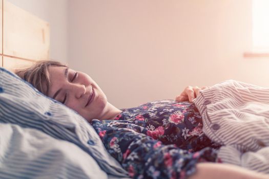 Young woman sleeping peacefully in her bedroom, day