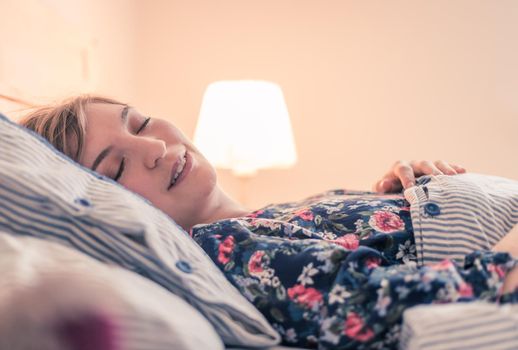 Young woman sleeping peacefully in her bedroom, day