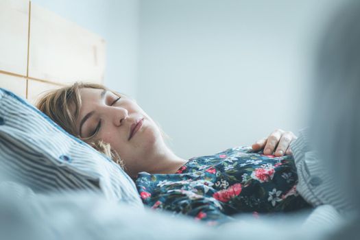 Young woman sleeping peacefully in her bedroom, day