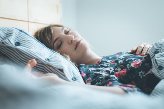 Young woman sleeping peacefully in her bedroom, day