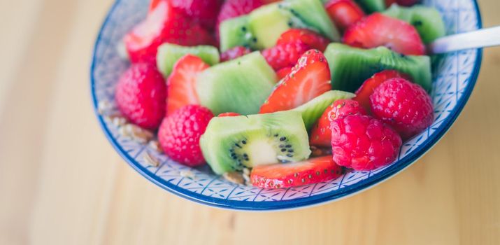 Close up of strawberries and kiwis in a ceramic bowl