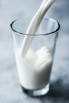 Dairy, healthy nutrition and breakfast concept - World Milk Day, pouring into glass on marble table