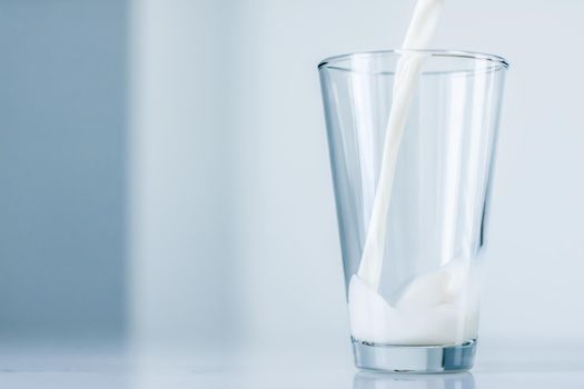 Dairy, healthy nutrition and breakfast concept - World Milk Day, pouring into glass on marble table