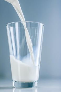 Dairy, healthy nutrition and breakfast concept - World Milk Day, pouring into glass on marble table