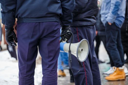 police officer holding loudspeaker megaphone at daylight, close-up with selective focus