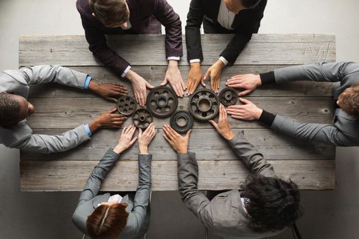 Business people connect gear together at meeting table, success cooperation teamwork concept