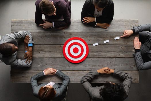 Team of business people pointing at red target at meeting table