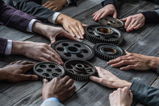 Business people connect gear together at meeting table, success cooperation teamwork concept