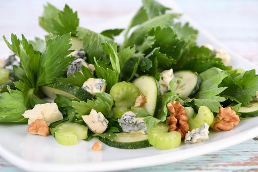 Celery leaves and stalks salad with fresh cucumber slices, blue cheese, crushed nuts.