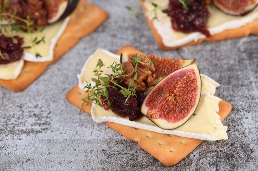 Cracker with a slice of camembert, jam, figs and nuts.
A great snack idea for a holiday, picnic or party.
