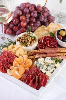 Delicacy assorted appetizer platter of salami and cheese, grissini wrapped in Parma ham, olives and citrus fruits. An original antipasto serving for a party.