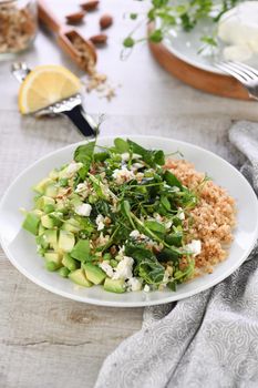 Gluten-free green vegetarian salad made of microgreen sprouts peas, avocado, quinoa, spinach, seasoned  crushed almonds with slices of feta cheese