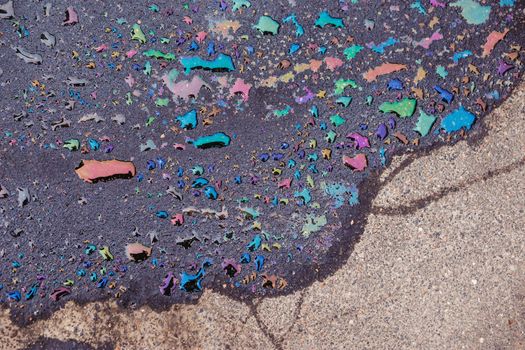 Abstract background, colorful stain of gas or oil on the asphalt caused by a leak from a car. Environmental pollution concept.