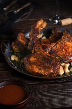 Juicy, slice of fried pork chop on a bone in oil with garlic and herbs in a pan. Close-up.