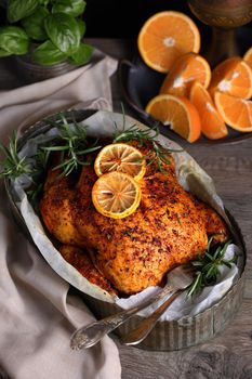 Baked whole chicken in spices with crispy appetizing fried crust in a tray, dark moody  