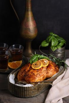 Baked whole chicken in spices with crispy appetizing fried crust in a tray, dark moody  