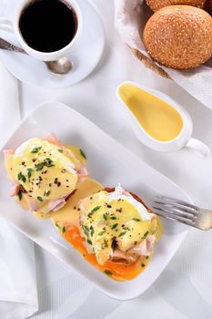Hollandaise butter sauce in a gravy boat for breakfast served with Eggs Benedict- fried English bun, ham, poached eggs, a cup of coffee