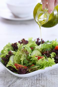 Pour the vegetable salad with lemon - olive dressing from butter-boat