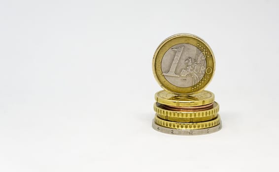 Various euro coins stacked with one euro coin standing on top. Coins isolated on a white background. Economics and finance. European Union currency.