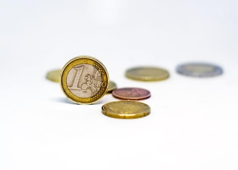 One euro coin standing together with various scattered coins isolated on a white background. Economics and finance. European union currency