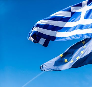 European political news, grexit and nation concept - Flags of Greece and European Union on blue sky background, politics of Europe