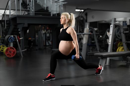 Pregnant fitness woman doing lunges exercises for leg muscle workout training in gym. Active girl doing front forward one leg step lunge exercise Caucasian female athletic woman
