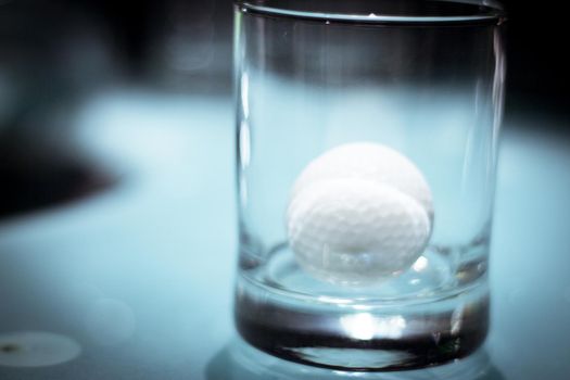 Golf ball inside a clear glass cup. No people